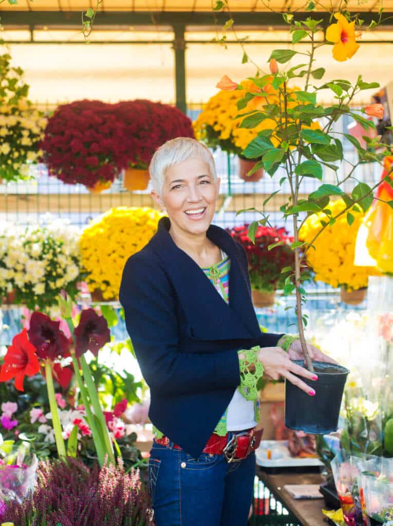 A lady holds a tall plant in a pot inside a California market near Fallbrook.