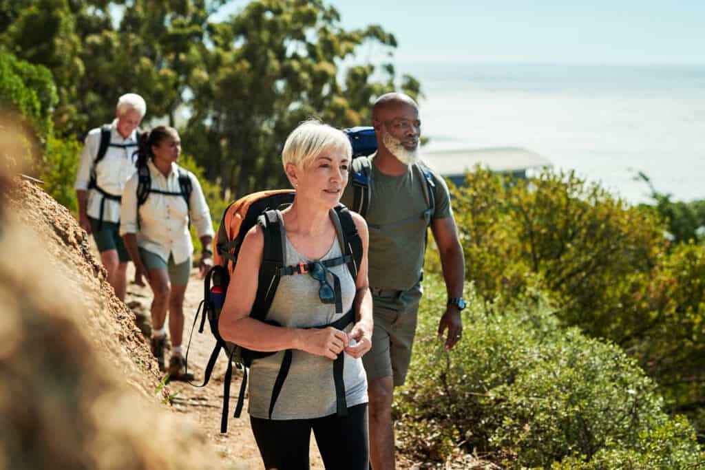 A group of four persons carrying backpacks, enjoy the nice sunny weather on a hiking trail near San Diego, California.